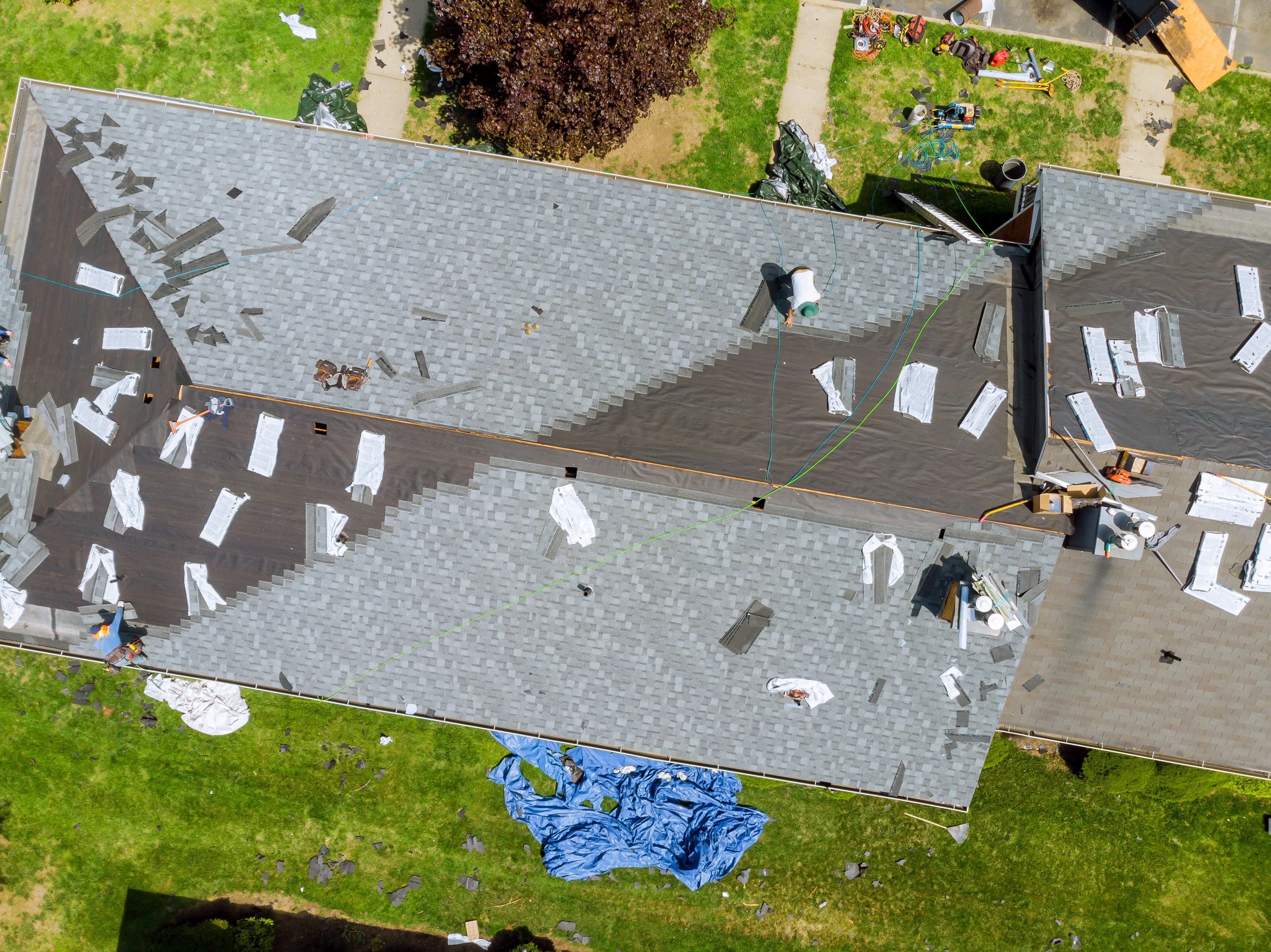 Roofer replacing damaged asphalt shingles on a residential roof.